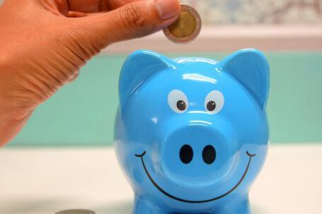 Investment Glossary. - Person Putting Coin in a Piggy Bank