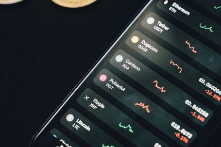 Online Investing - Coins scattered near smartphone with financial charts on screen
