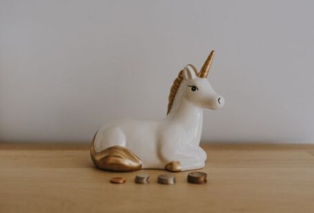 Investment Basics - white and gold ceramic unicorn figurine near coins