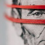 Investment Basics - Closeup of rolled United States five dollar bills tightened with red rubber band